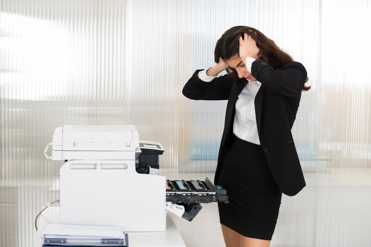 Irritated Businesswoman Looking At Printer Machine At Office
