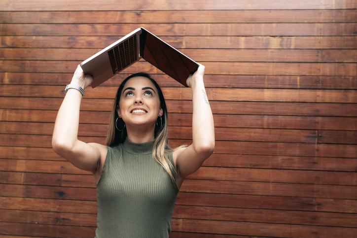 young brazilian woman holding laptop over head